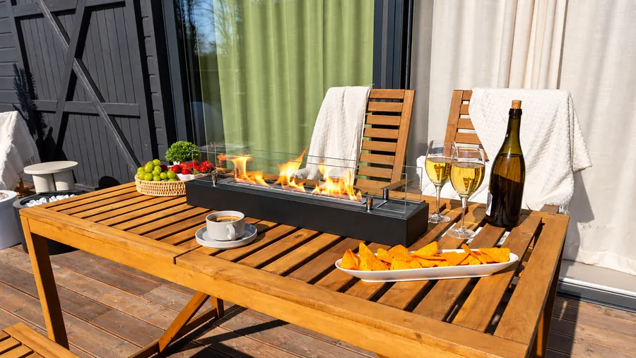 Langer Tischkamin auf einem Holztisch mit Wein und Snacks