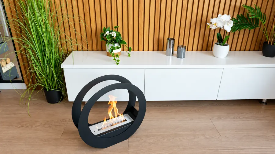 Ovaler schwarzer Ethanol Kamin vor einem weißen Sideboard