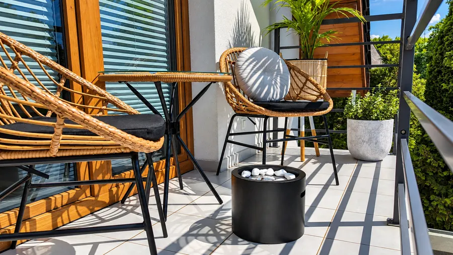 Schwarze Feuerstelle auf dem Balkon mit Rattanstühlen